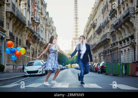 Couple romantique courant dans la rue avec la tour Eiffel en arrière-plan à Paris, France Banque D'Images