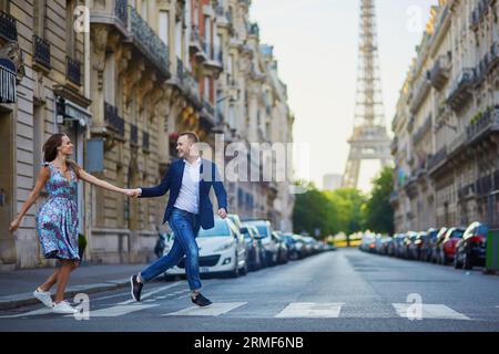 Couple romantique courant dans la rue avec la tour Eiffel en arrière-plan à Paris, France Banque D'Images