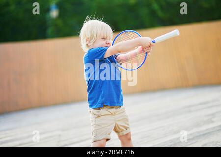 Adorable petit garçon jouant au badminton sur l'aire de jeux. Activités estivales en plein air pour les enfants Banque D'Images