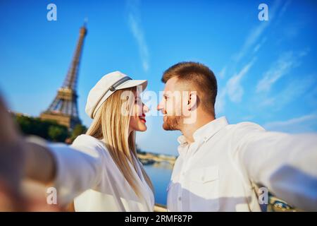 Heureux couple prenant selfie près de la tour Eiffel. Touristes profitant de leurs vacances en France. Date romantique ou concept de couple voyageur Banque D'Images