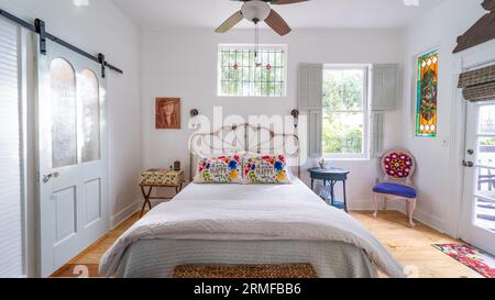 Une chambre confortable et accueillante avec un lit blanc décoré avec une variété d'oreillers vibrants Banque D'Images