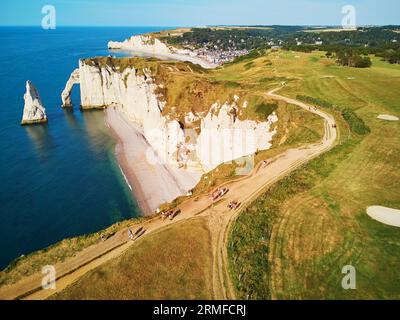 Les gens marchent au sommet de la falaise, profitant du paysage panoramique pittoresque des falaises de craie blanche, des arches naturelles et des terrains de golf d'Etretat, Seine-M. Banque D'Images