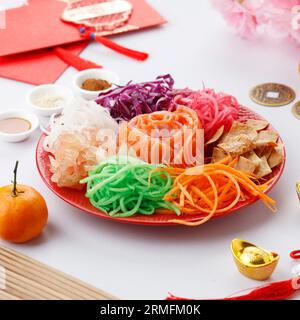 Yusheng, Yee sang ou Yuu Sahng se compose généralement de lanières de saumon cru, de légumes hachés mélangés, de sauces et de condiments Banque D'Images