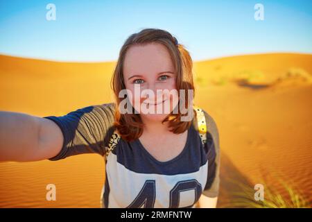 Heureux touriste souriant prenant selfie avec des dunes de sable dans le désert du Sahara, à Erg Chebby, Merzouga, Maroc Banque D'Images