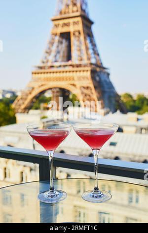 Deux cocktails cosmopolites dans des verres à martini traditionnels sur une table en verre avec vue sur la tour Eiffel, Paris, France Banque D'Images