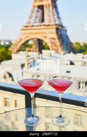 Deux cocktails cosmopolites dans des verres à martini traditionnels sur une table en verre avec vue sur la tour Eiffel, Paris, France Banque D'Images