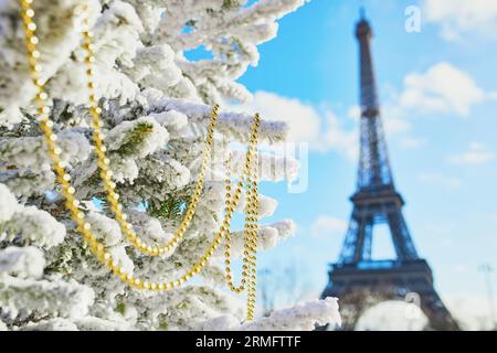 Sapin de Noël recouvert de neige et décoré de perles près de la tour Eiffel à Paris. Célébration des vacances saisonnières en France Banque D'Images