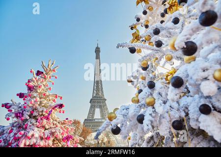 Arbres de Noël décorés recouverts de neige près de la tour Eiffel à Paris, France Banque D'Images