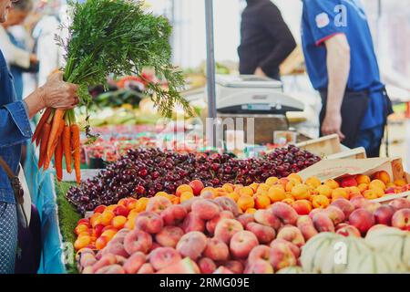 Femme achetant des légumes et des fruits biologiques frais sur le marché fermier à Paris, France. Marché européen typique des produits locaux Banque D'Images