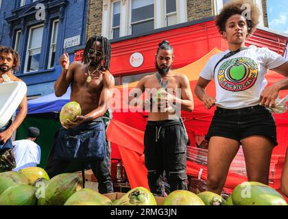 Londres, Royaume-Uni. 28 août 2023. Au stand 'Coconut King', les boissons sont préparées avec des noix de coco fraîchement coupées. Après le défilé, les foules se rassemblent dans la rue et autour des nombreux systèmes de sonorisation et stands de nourriture le lundi du Carnaval. Jusqu'à deux millions de personnes sont attendues pour célébrer le carnaval ce week-end de vacances de la Banque en participant ou en regardant. Crédit : Imageplotter/Alamy Live News Banque D'Images