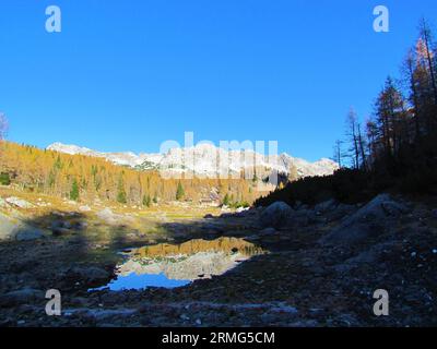 Vue de Lodge de montagne à Triglav lacs vallée avec des pics de montagne rocheux et automne doré forêt de mélèze à l'arrière et petit lac avec un refl Banque D'Images