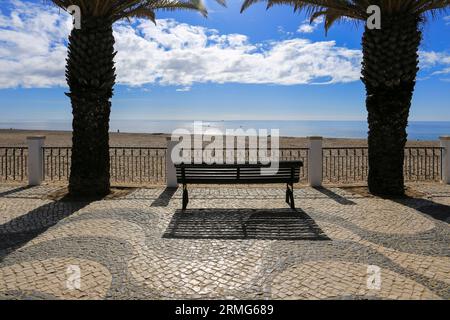 Belle promenade pavée avec banc avec vue sur la plage de Praia da Luz dans l'Algarve, Portugal Banque D'Images