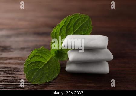 Savoureux chewing-gums blancs et feuilles de menthe sur la table en bois, gros plan Banque D'Images