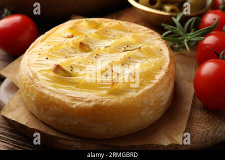 Savoureux fromage brie cuit au four avec romarin et tomates cerises sur planche de bois, gros plan Banque D'Images