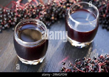 Sirop de sureau noir maison dans deux verres avec des fruits frais Banque D'Images