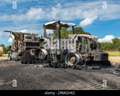 Restes brûlés de tracteur agricole dans un champ suite à un incendie qui a totalement détruit le tracteur et la presse à balles, Leicestershire, Angleterre, Royaume-Uni Banque D'Images