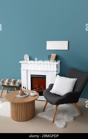 Table basse avec tasse de thé, verseuse et bougies dans le salon Banque D'Images