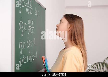 Jeune professeur de mathématiques fatigué près du tableau noir dans la salle de classe Banque D'Images