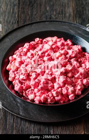 salade crémeuse aux canneberges avec mini guimauves, pomme fraîche et noix de pécan dans un bol noir sur une table en bois sombre, vue verticale d'en haut, gros plan Banque D'Images
