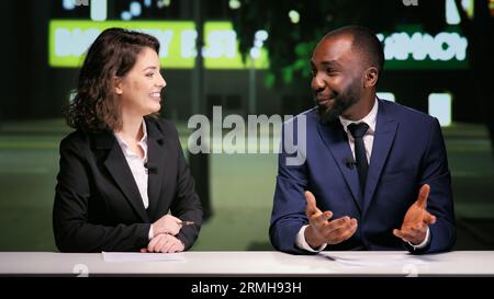 L'équipe des diffuseurs dans un talk-show nocturne abordant différents sujets d'actualité en direct dans la salle de rédaction, organisant un panel de divertissement dans un programme télévisé. Divers journalistes de médias présentant le segment de minuit. Banque D'Images