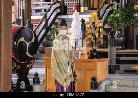 Japon, Fukuoka, Hakata. Prêtre shinto exécutant une cérémonie pour un fidèle au sanctuaire shinto de Kushida. Banque D'Images