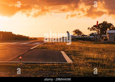 Les couleurs or et orange du coucher du soleil frappent la piste de l'aéroport de Placencia, au sud-est du Belize Banque D'Images