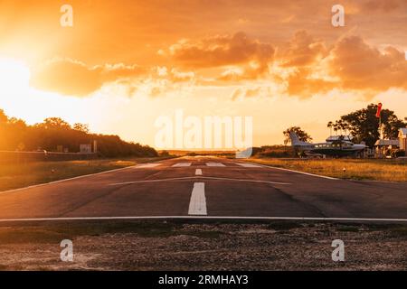 Les couleurs or et orange du coucher du soleil frappent la piste de l'aéroport de Placencia, au sud-est du Belize Banque D'Images