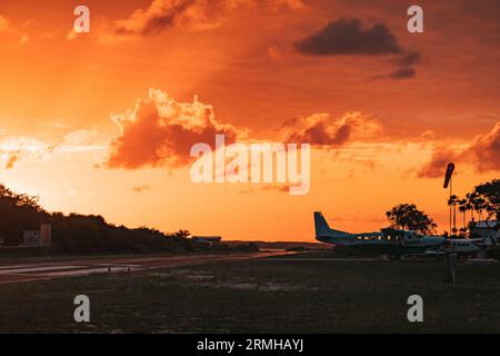 Les couleurs or et orange du coucher du soleil frappent la piste de l'aéroport de Placencia, au sud-est du Belize Banque D'Images