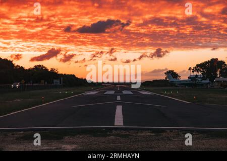 Les couleurs or et orange du coucher du soleil frappent la piste de l'aéroport de Placencia, au sud-est du Belize Banque D'Images