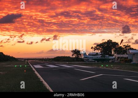 Les couleurs or et orange du coucher du soleil frappent la piste de l'aéroport de Placencia, au sud-est du Belize Banque D'Images