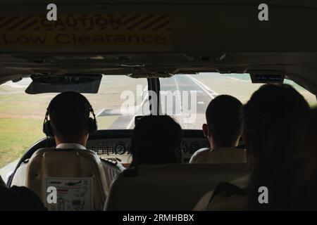 Silhouettes de passagers contre la piste arrivant pour atterrir dans un petit avion à l'aéroport international Philip S.W. Goldson de Belize City Banque D'Images