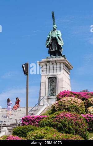 Japon, Kyushu, Fukuoka, Hakata. Parc Higashi. Femmes faisant une photo par Statue de l'empereur Kameyama-Joko, 1249-1305. Banque D'Images