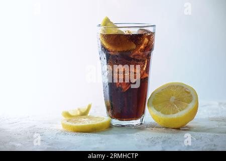 Cola frais avec des glaçons et des tranches de citron dans un verre à boire sur un fond gris bleu clair, boisson rafraîchissante de caféine douce, espace de copie, sele Banque D'Images