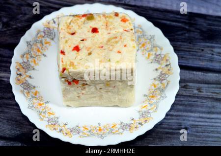 Une assiette avec un cube de baril égyptien Baramily fromage blanc avec des tranches de poivrons rouges et verts, un fromage traditionnel du Moyen-Orient à base de pasteur Banque D'Images