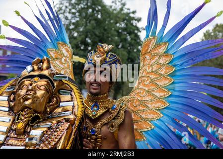 Un danseur de samba masculin est habillé en costume de style égyptien et poussant le cercueil de Toutankhamon pendant le défilé. Le Carnaval de Notting Hill est l'un des plus grands festivals de rue au monde. Il a commencé en 1966 mais a commencé avec le carnaval des Caraïbes organisé en 1959 avec la communauté immigrée de Trinité-et-Tobago. Cette année, le Carnaval de Notting Hill marque le 50e anniversaire de l'introduction des systèmes sonores et des groupes Mas. Il marque également le 75e anniversaire de l'arrivée des passagers de l'Empire Windrush au Royaume-Uni. Banque D'Images