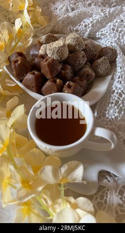 Gros plan d'une petite assiette contenant un assortiment de biscuits au sucre fraîchement cuits avec une tasse de thé Banque D'Images