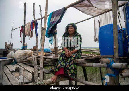 26 août 2023, Khulna, Bangladesh : Mohiful Begum (35 ans) pose pour une photo devant sa maison endommagée dans une zone côtière à Kalabogi. Il n'y a pas si longtemps, Kalabogi, un village côtier du Bangladesh, était plein de terres cultivables jusqu'à ce que la montée du niveau de la mer commence à envahir la région jusqu'au golfe du Bengale. De fréquents cyclones et inondations frappent le village depuis la fin des années 1990 En 2009, un cyclone majeur nommé Aila a détruit les 1 400 kilomètres de remblais du pays, 8 800 kilomètres de routes et environ 3 50 000 acres de terres agricoles. Plusieurs centaines de personnes auraient été tuées dans le di Banque D'Images