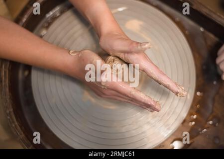 Potter girl travaille sur la roue de potier, faisant pot en céramique à partir d'argile dans l'atelier de poterie. Art et concept de passe-temps Banque D'Images