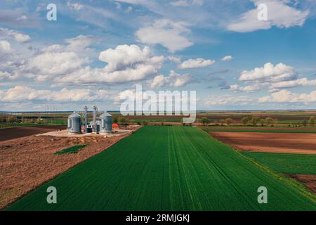 Silos de ferme dans le champ, vue aérienne du drone pov le jour ensoleillé du printemps Banque D'Images