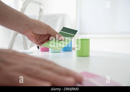 Gros plan des mains de l'homme choisissant la couleur de peinture des échantillons de couleur Banque D'Images