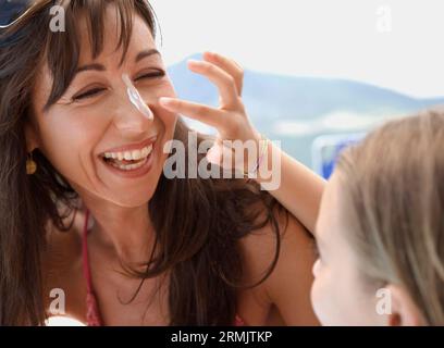 Fille d'appliquer un écran solaire sur le nez de la mère Banque D'Images