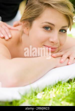 Jeune femme allongée sur l'herbe de recevoir un massage Banque D'Images