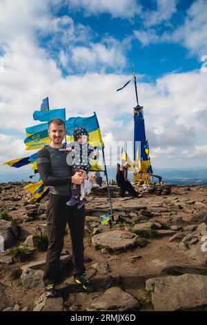 Un homme avec un bébé sur la montagne près des drapeaux ukrainiens Banque D'Images