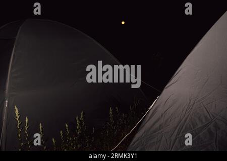 Vue nocturne : Camping à Uttarakhand, Inde, avec des campings de premier plan, sous la vue captivante d'une pleine lune de sang. Banque D'Images