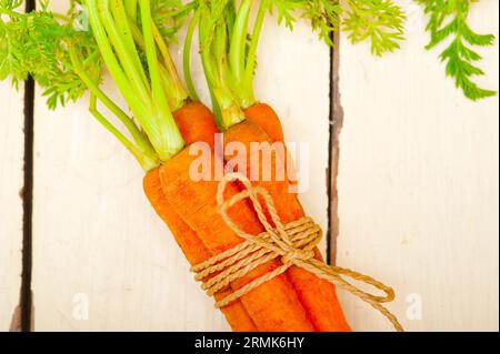 Bouquet de carottes fraîches avec corde sur une table rustique Banque D'Images