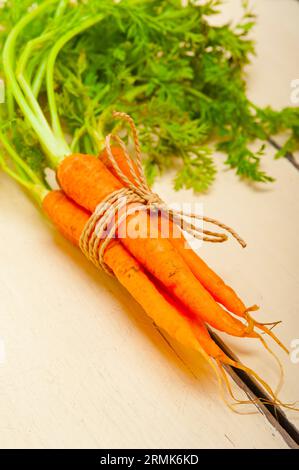 Bouquet de carottes fraîches avec corde sur une table rustique Banque D'Images