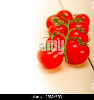 Tomates cerises fraîches sur un groupe de tomates sur une table en bois rustique Banque D'Images
