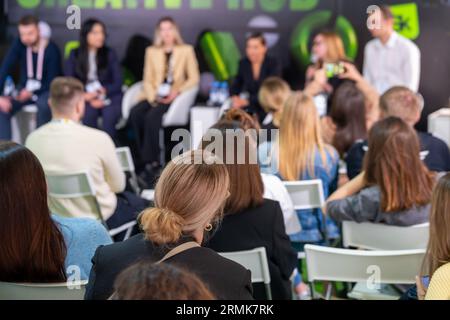 Vue arrière de personnes méconnaissables se rassemblant et prenant part à une convention en écoutant les gens sur scène Banque D'Images