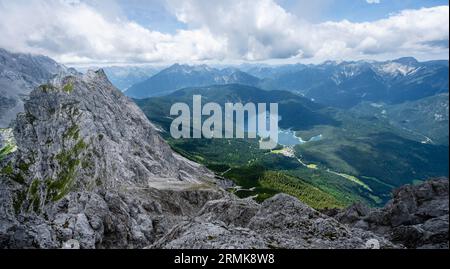 Vue depuis le sommet du Waxenstein, vue sur la crête rocheuse et étroite de la crête de Waxenstein jusqu'au lac Eibsee, paysage montagneux rocheux nuageux Banque D'Images