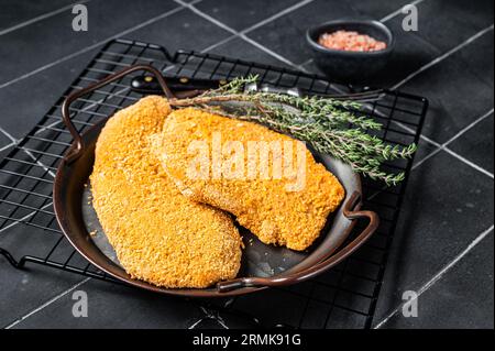 Weiner Schnitzel allemand, cru et fait maison. Arrière-plan noir. Vue de dessus. Banque D'Images